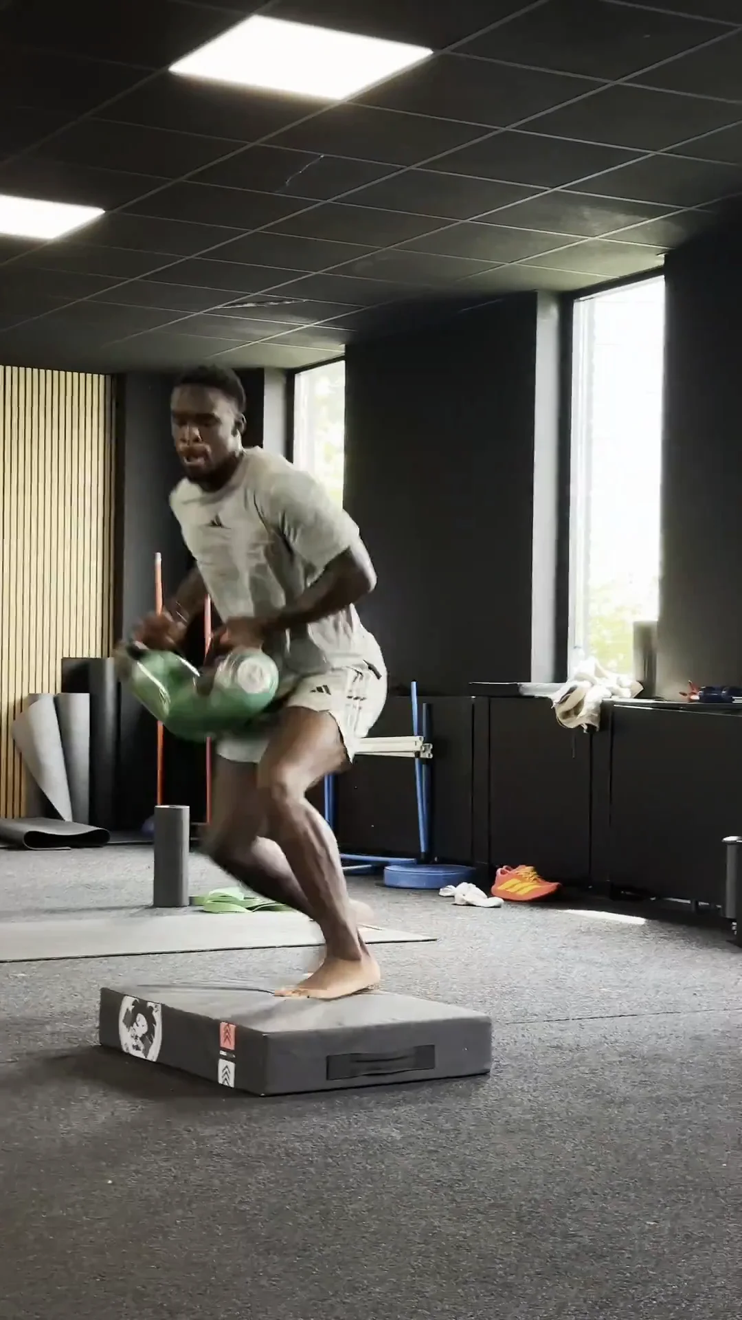 Athlete performing lateral jumps holding a water-filled power bag